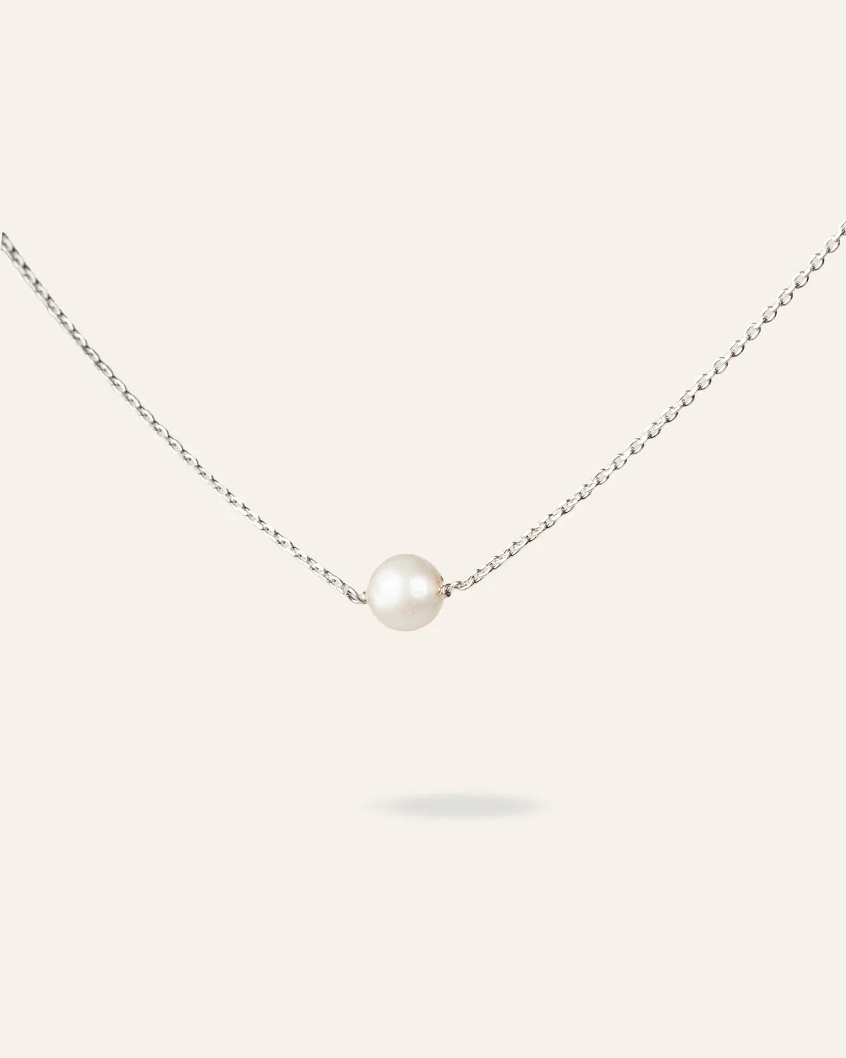 Collier MoonRose La Perle de Foi en or avec une perle élégante, porté sur un fond neutre.